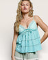 Woman wearing a light blue top with lace details on a plain background