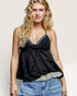 Woman wearing a black top and blue jeans with a beige background