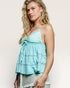 Woman wearing a light blue top with thin straps against a plain background