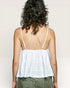 Person wearing a white top with thin straps on a plain background
