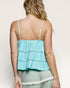 Woman wearing a light blue top with thin straps on a plain background