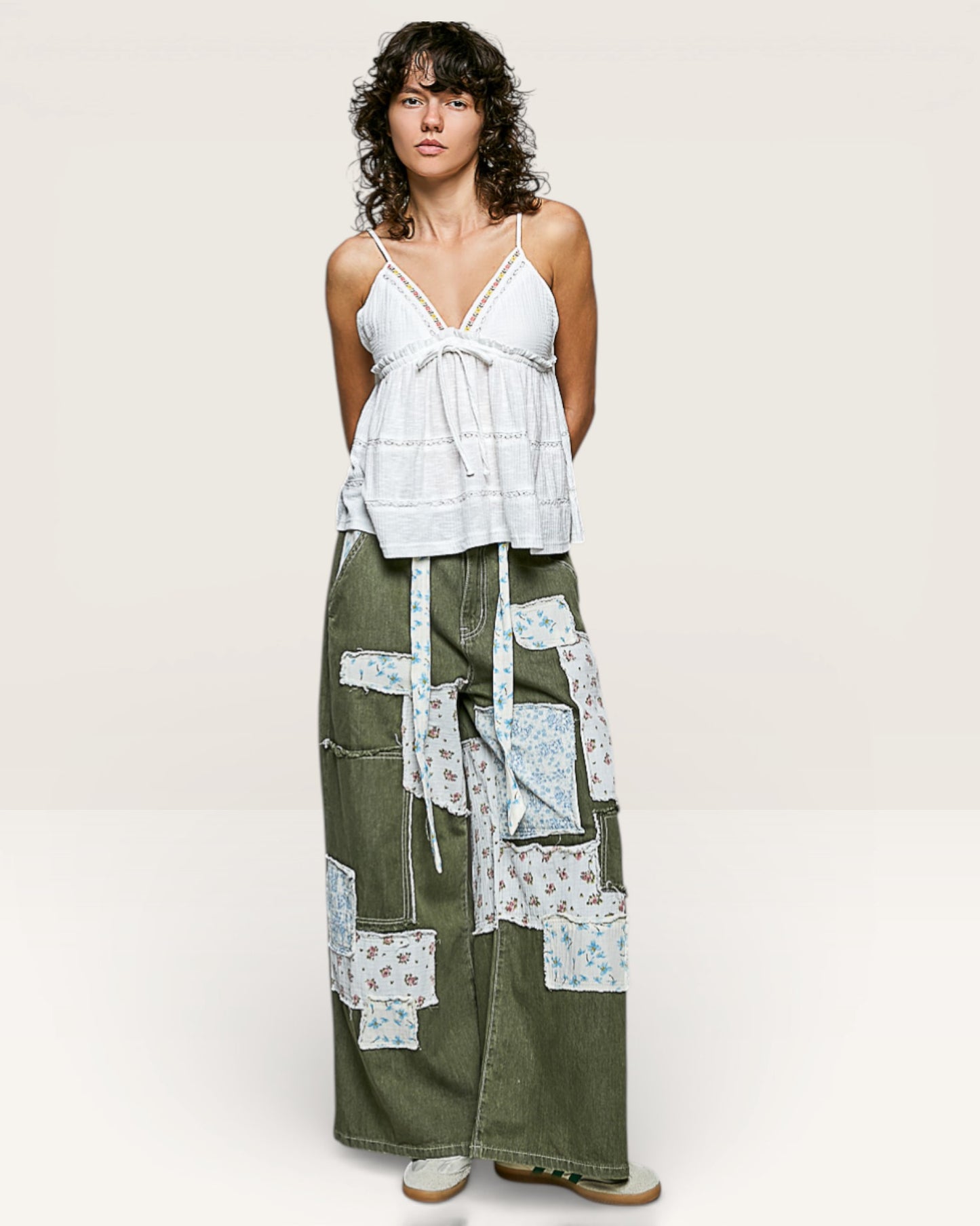 Woman wearing a white top and green patchwork pants on a white background