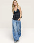 Woman wearing a black tank top and blue jeans on a white background