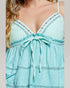 Close-up of a turquoise dress with floral lace details on a neutral background