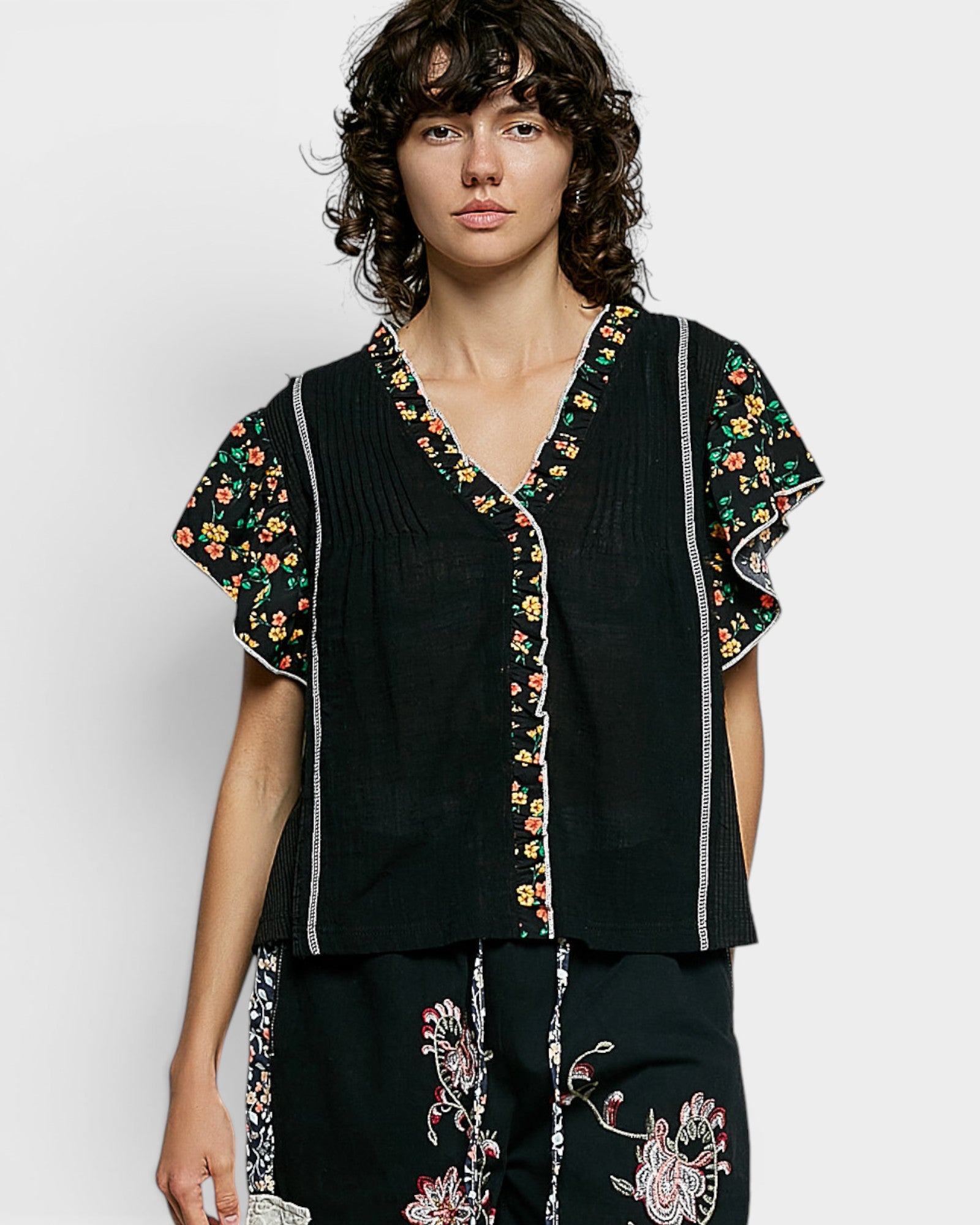 Woman wearing a black outfit with floral embroidery on a white background