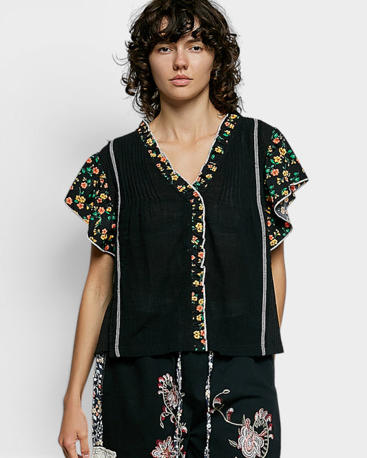 Woman wearing a black outfit with floral embroidery on a white background