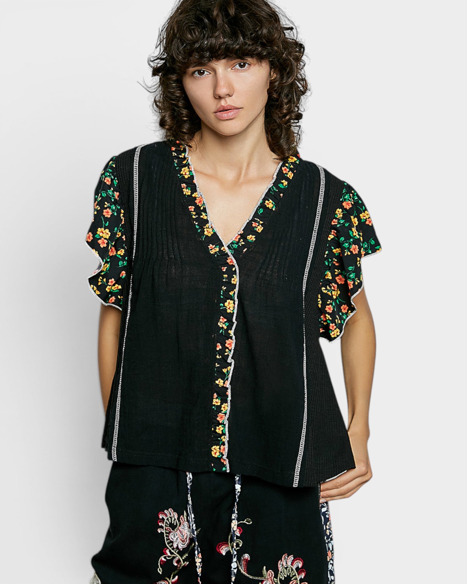 Woman wearing a black outfit with floral embroidery on a white background