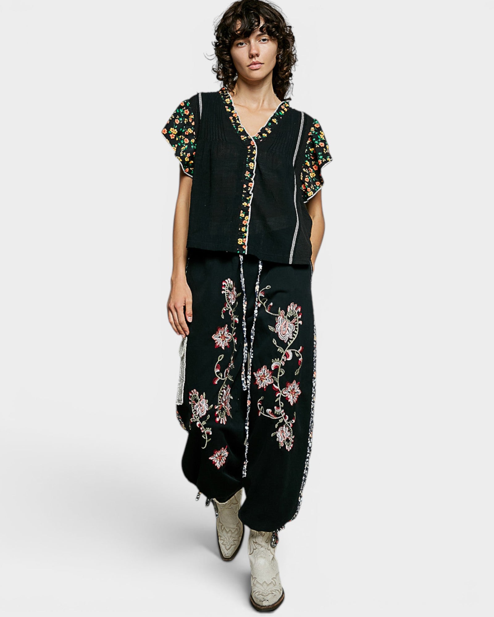 Person wearing a black outfit with floral embroidery on a white background