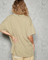 Person wearing a beige oversized shirt against a gray concrete wall