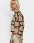 Woman wearing a patterned cardigan with hearts and geometric shapes on a plain background