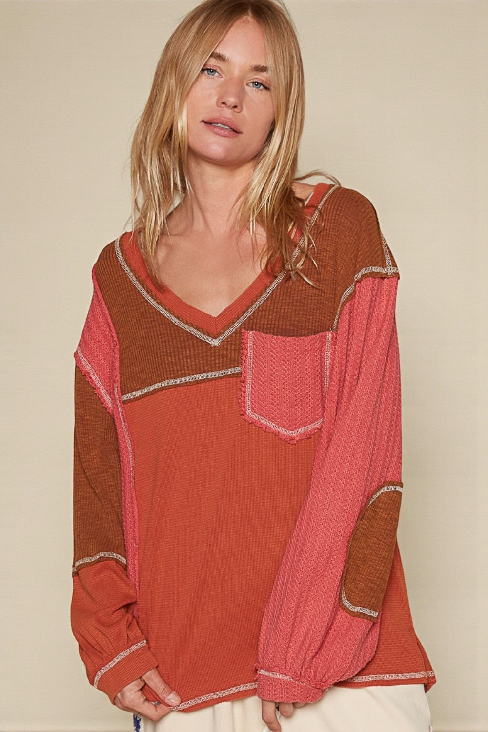 Woman wearing a red and brown patterned top against a beige background