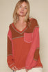 Woman wearing a red and brown patterned top against a beige background