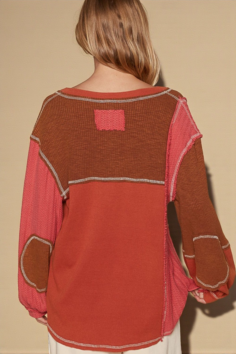 Red and brown sweater with patchwork design on a beige background