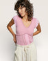 Woman wearing a pink top with lace details on a plain background