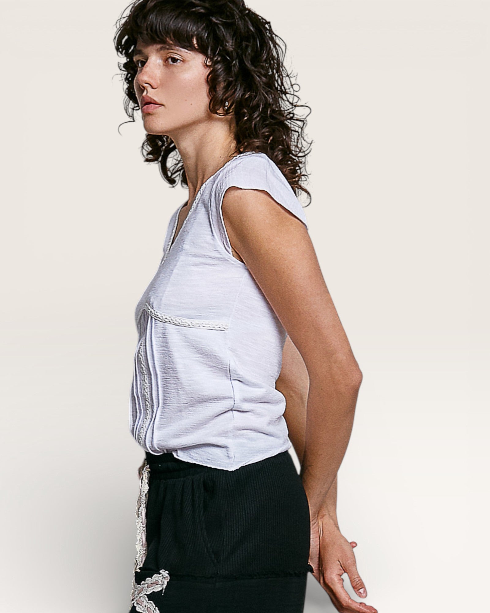 Woman wearing a light gray sleeveless top and black pants against a plain background