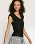 Woman wearing a black sleeveless top with a plain background