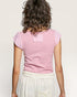 Person wearing a pink top and white pants on a plain background