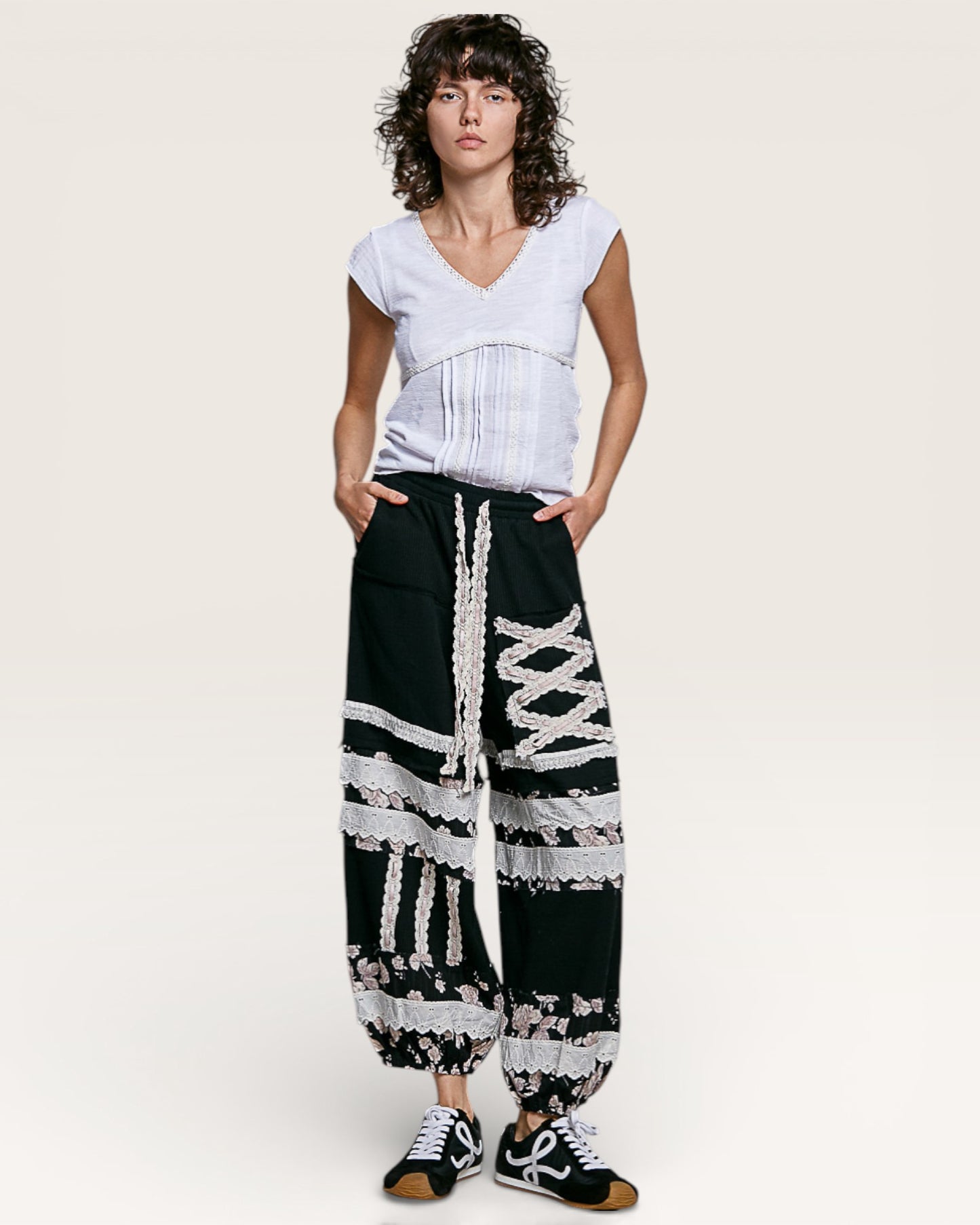 Woman wearing a white top and black and white patterned pants on a plain background