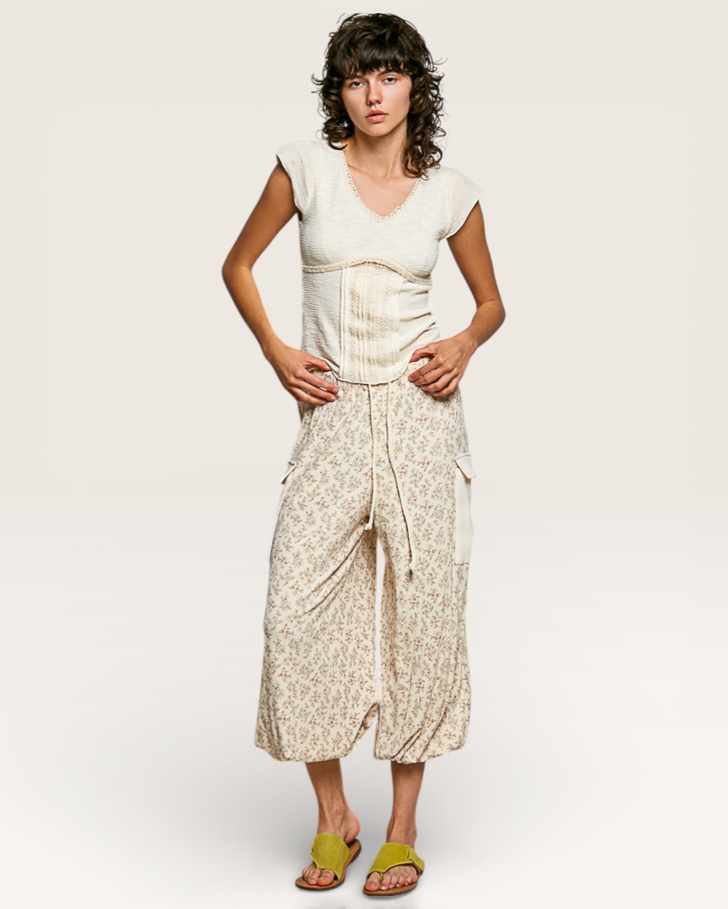 Woman wearing a white top and beige floral skirt on a plain background