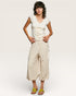 Woman wearing a white top and beige floral skirt on a plain background