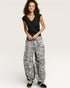 Person wearing a black top and patterned gray pants on a white background