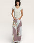 Woman wearing a white top and floral patchwork pants on a plain background