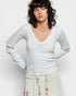 Woman wearing a light gray long-sleeve top against a plain background