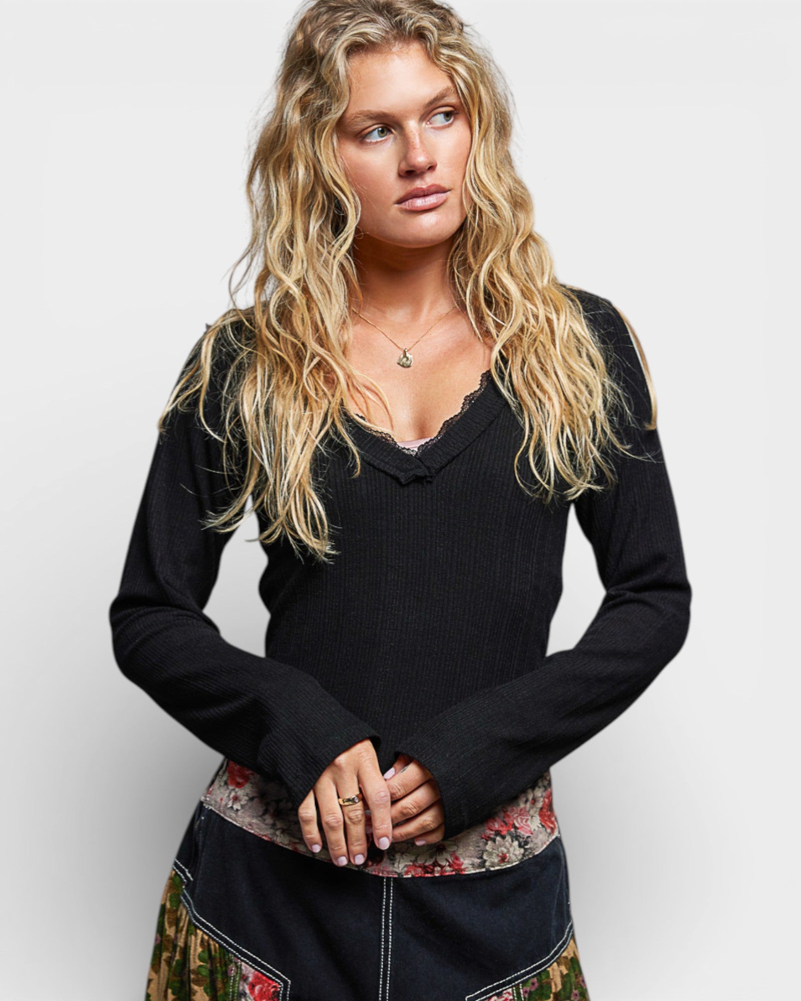Woman wearing a black sweater with a floral skirt on a white background