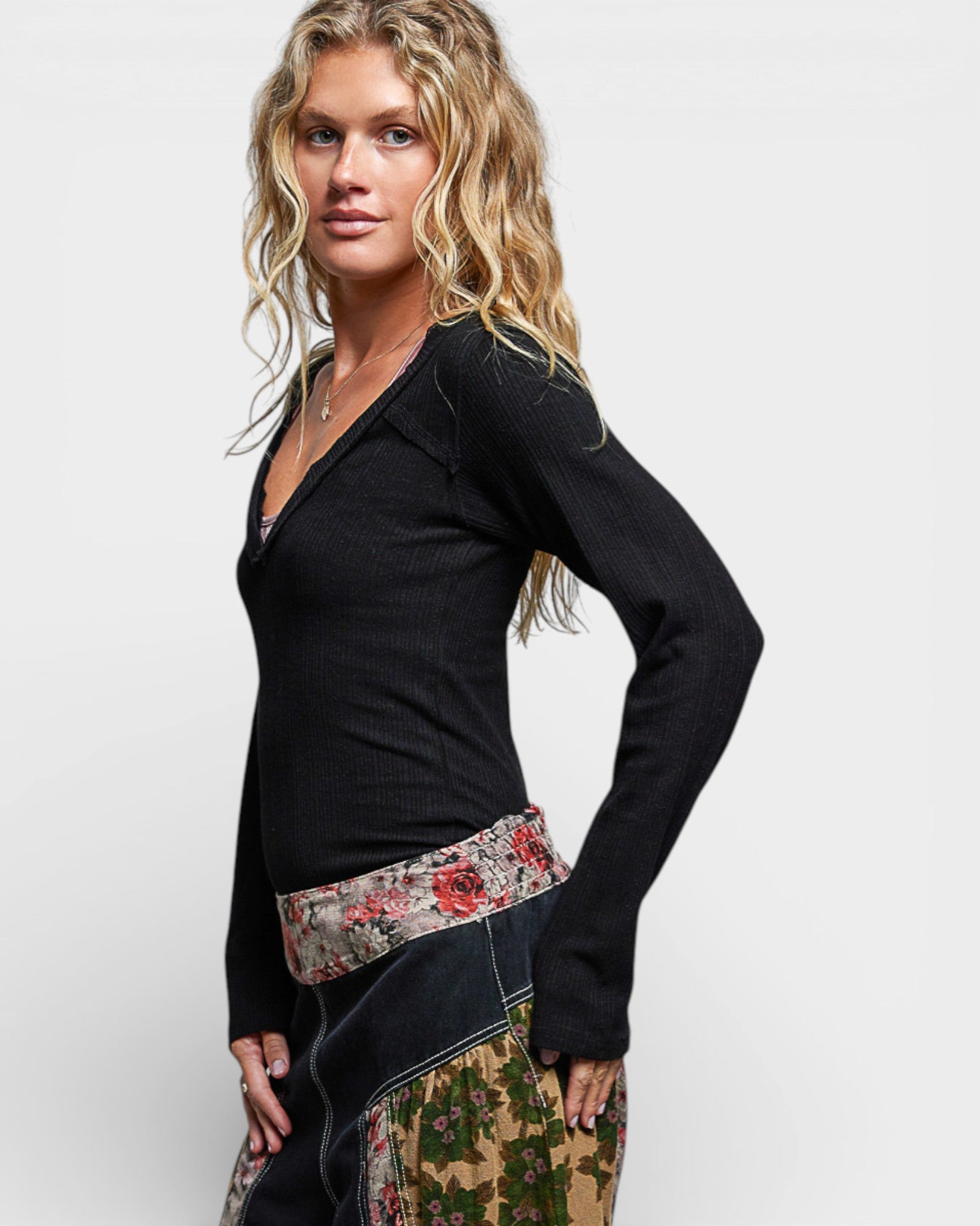 Woman wearing a black top with a floral belt and skirt on a white background