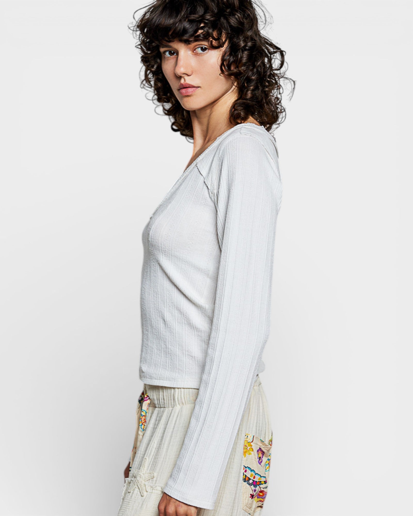 Woman wearing a light gray long-sleeve top with a plain background