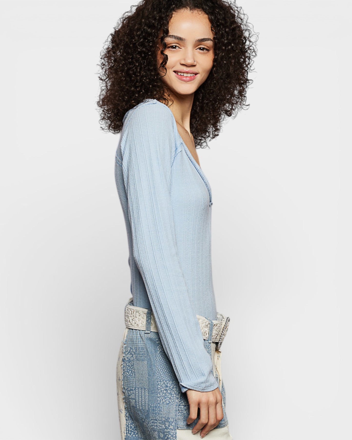 Woman wearing a light blue dress with lace details on a white background