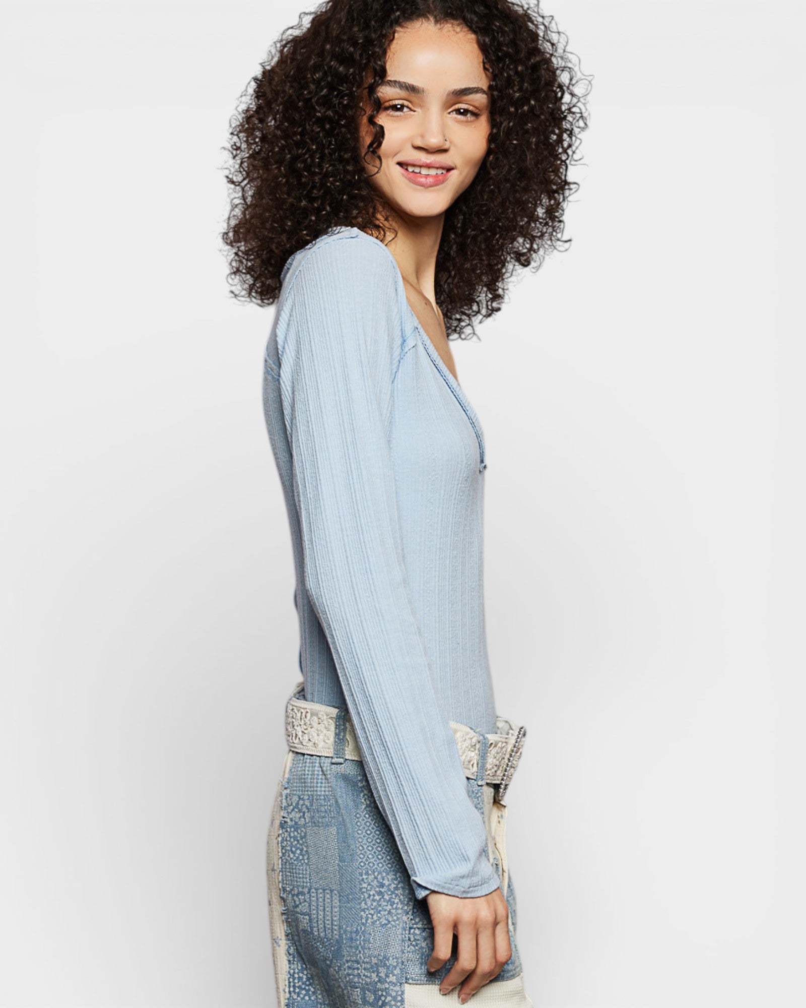 Woman wearing a light blue dress with lace details on a white background