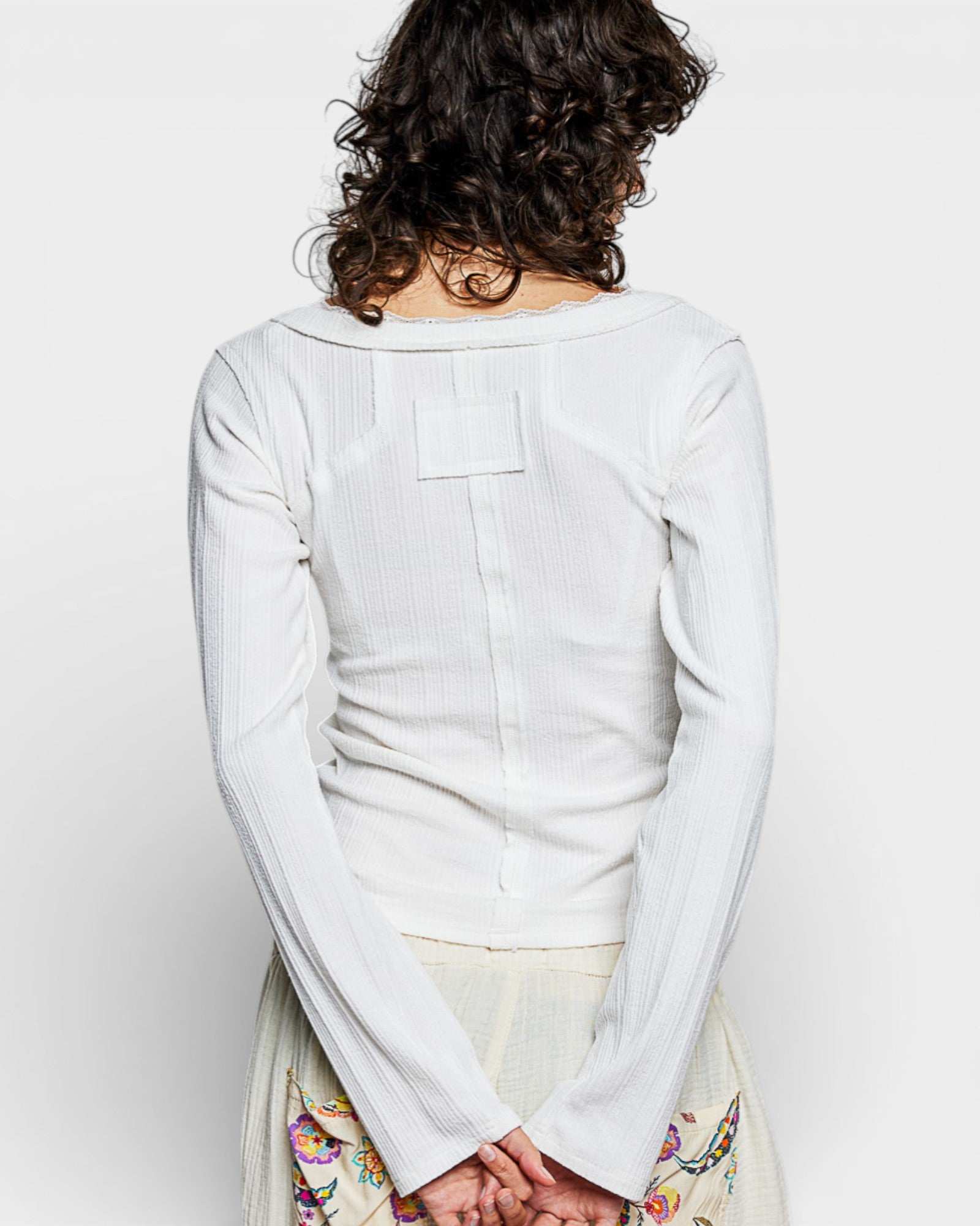 Person wearing a light gray long-sleeve shirt on a white background