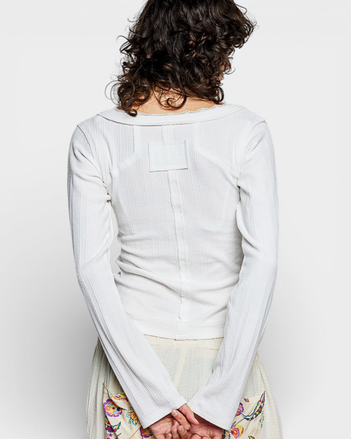 Person wearing a light gray long-sleeve shirt on a white background