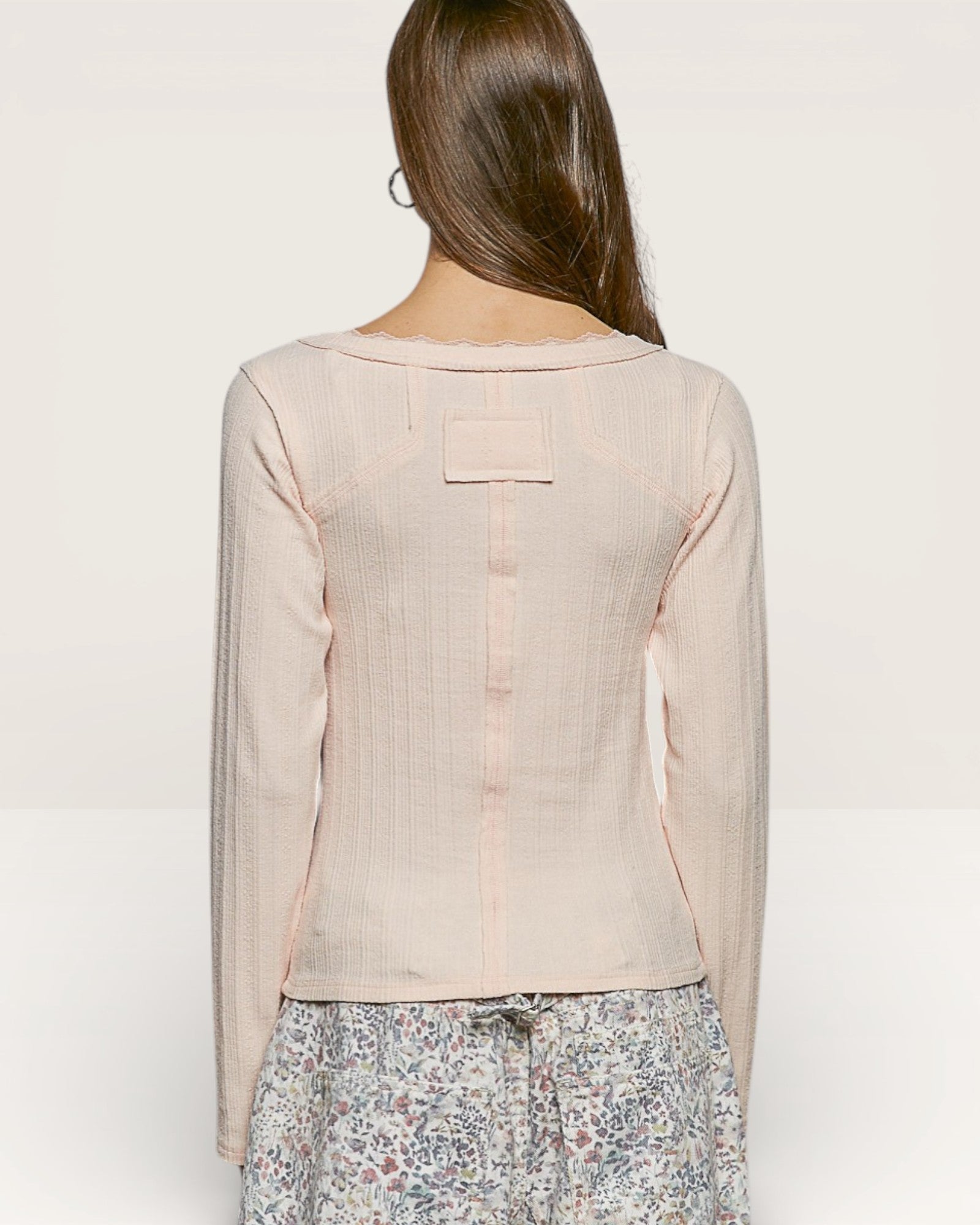 Woman wearing a light pink blouse with a subtle pattern on a plain background