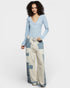 Woman wearing a light blue long-sleeve top and patchwork pants on a white background