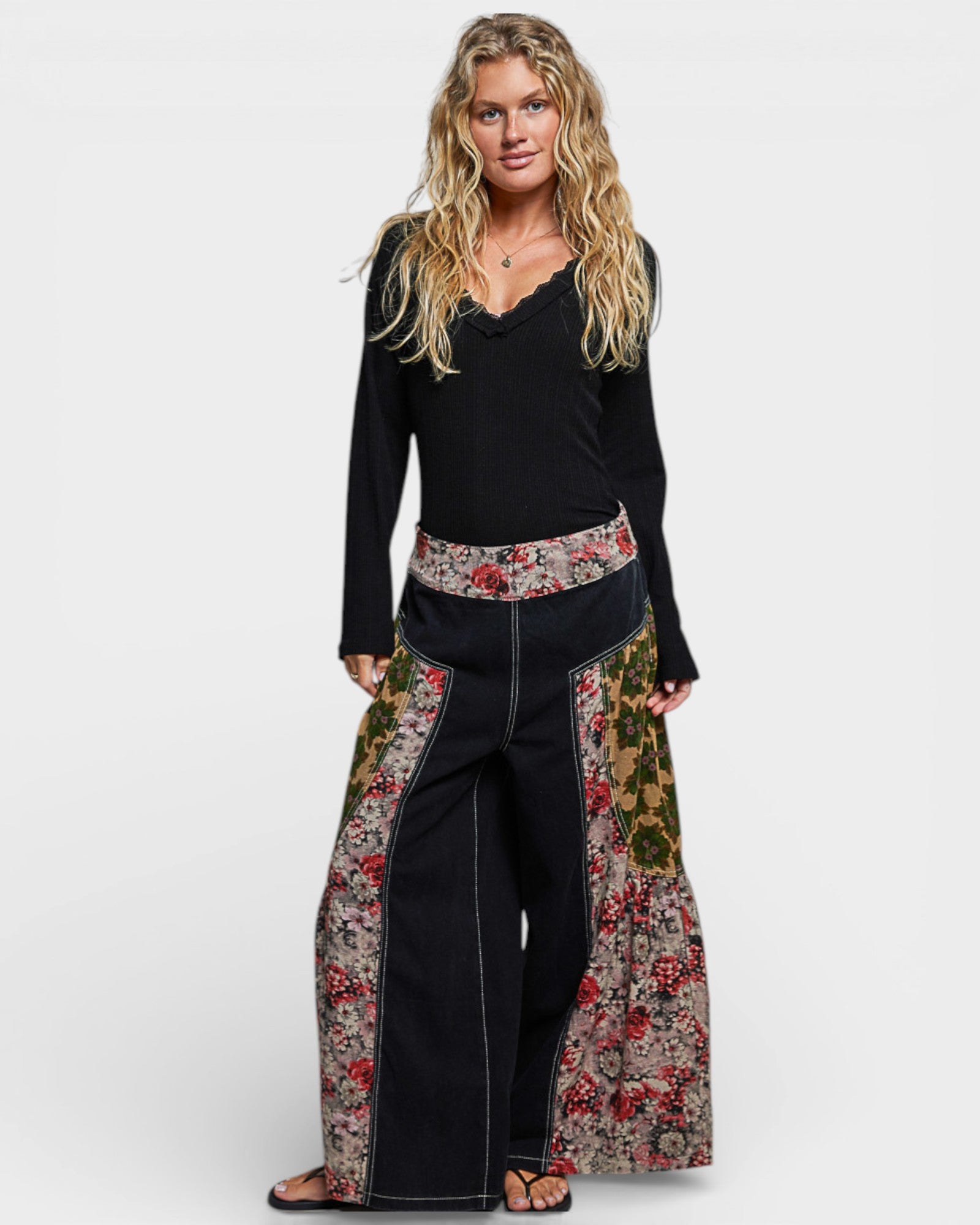 Woman wearing a black top and floral pants on a white background