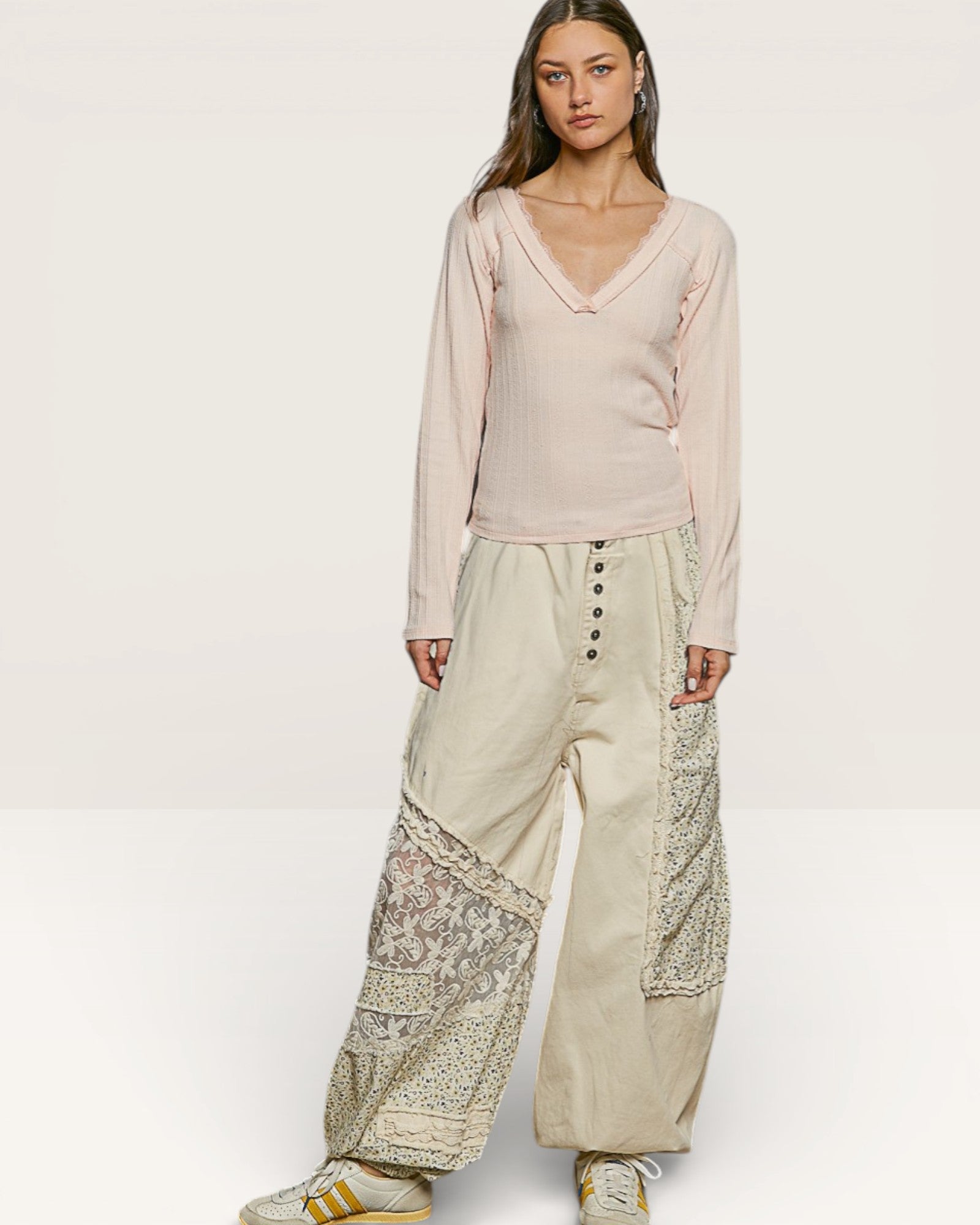 Woman wearing a light pink top and beige pants with floral patterns on a white background