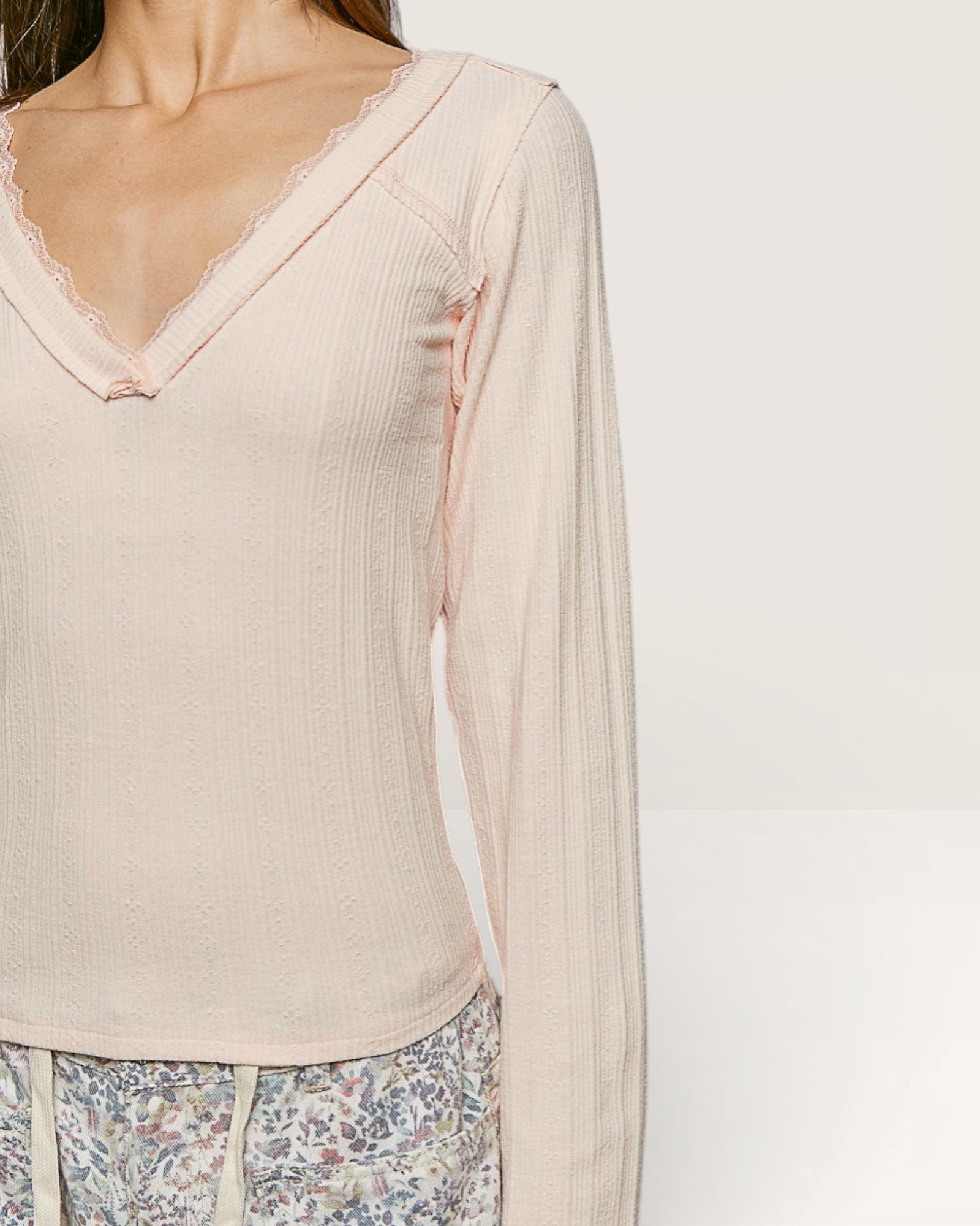 Beige long-sleeve top with floral pants on a plain background