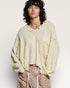 Person wearing a loose-fitting, cream-colored cardigan over a light shirt with leopard print pants on a plain background.