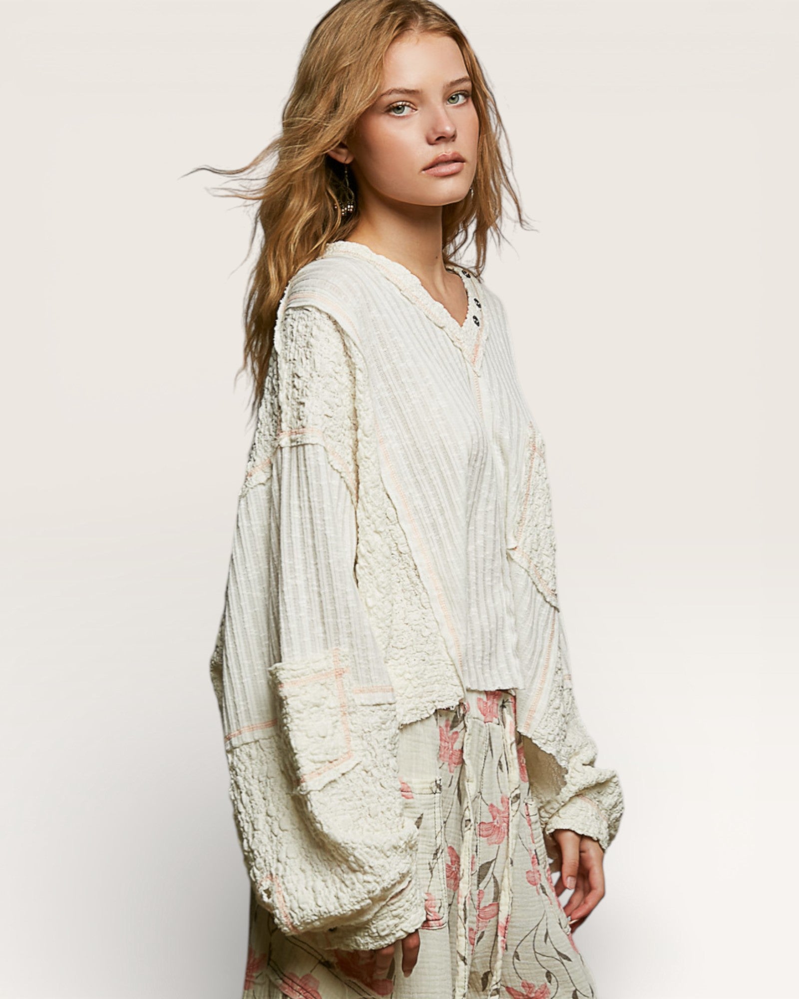 Woman wearing a white lace top with a plain background