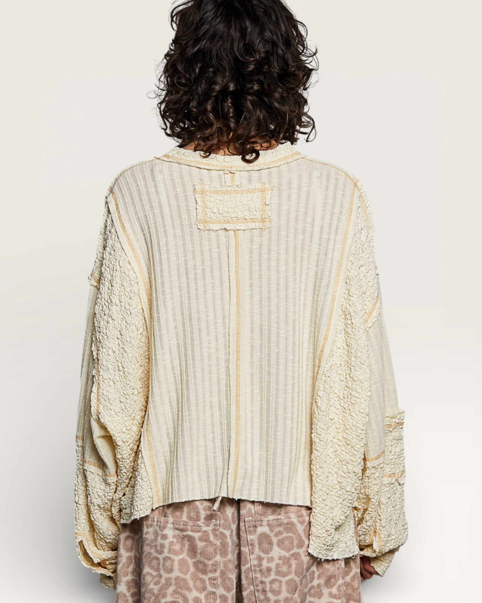 Person wearing a textured beige shirt with a plain background