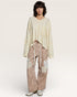 Person wearing a light-colored sweater and leopard print pants on a white background