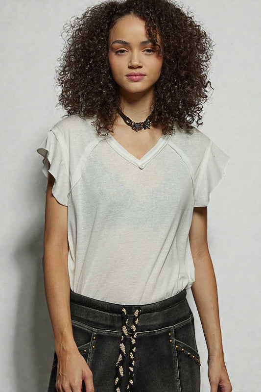 Woman wearing a light-colored top and dark pants against a plain background