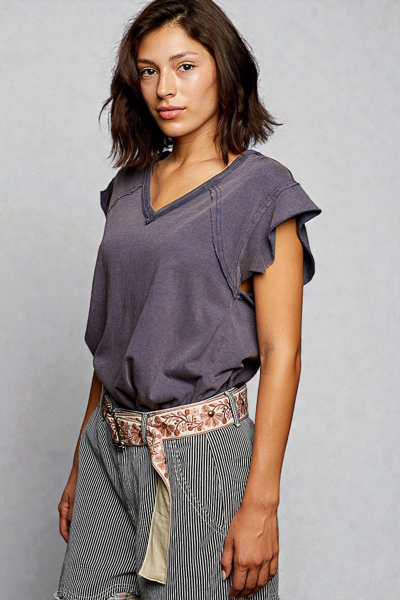 Woman wearing a loose-fitting purple top and striped pants against a plain background