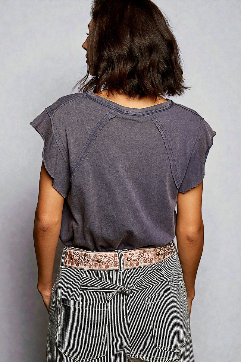 Person wearing a gray t-shirt and striped pants with a floral belt on a plain background