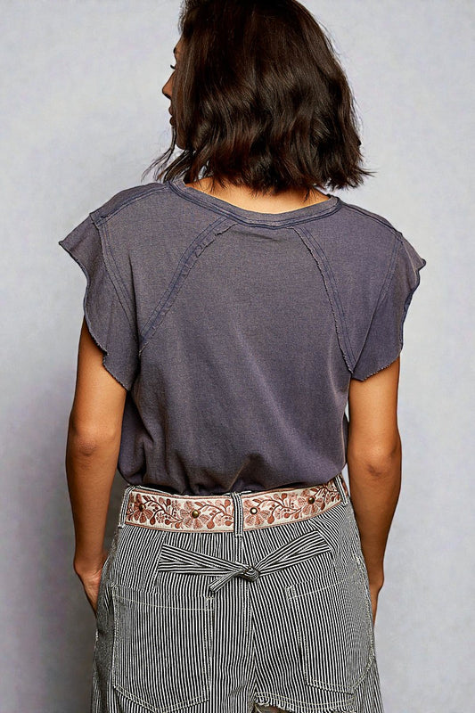 Person wearing a gray t-shirt and striped pants with a floral belt on a plain background