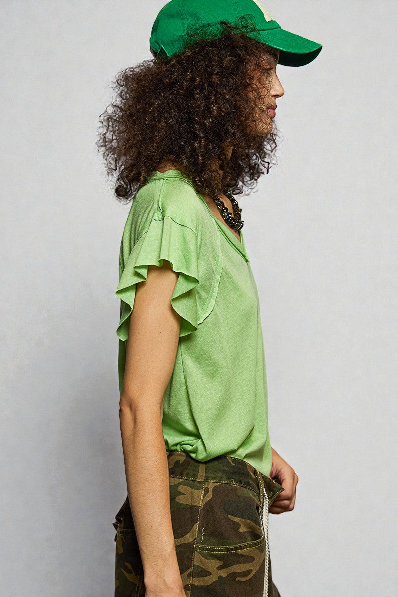Person wearing a green top and cap with camouflage pants on a plain background