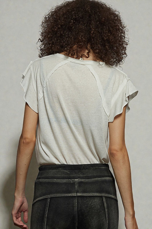 Person wearing a light-colored top and dark pants against a plain background