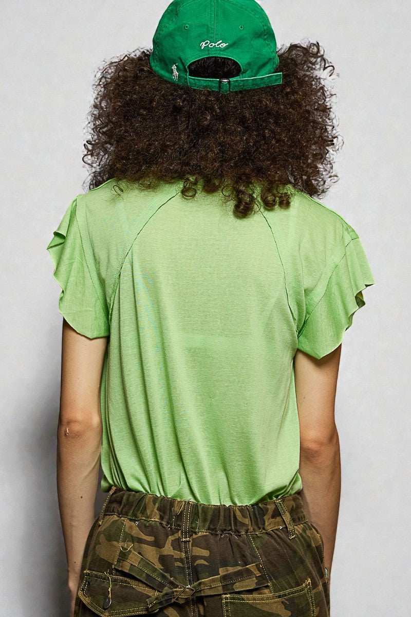 Person wearing a green t-shirt and cap with camouflage pants on a plain background